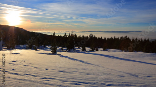 Snow covered mountains during sunset above clouds, Czechia.