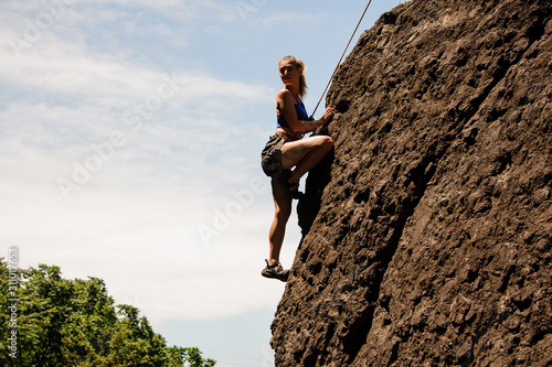 Female climber posing on a sheer rock
