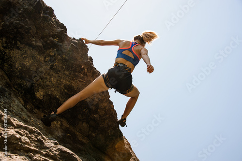 Sporty girl climbs on the top of the mountain