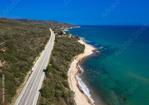 Aerial view of asphalt road without cars with green hils and blue sea wth waves