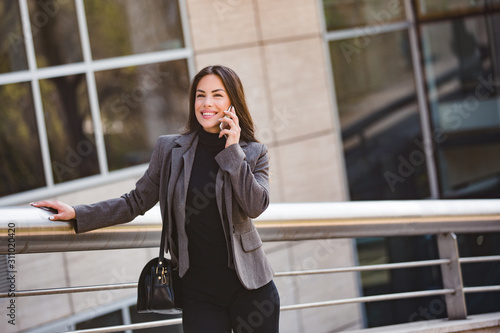 Business woman executive talk on a mobile phone, office buildings in the background © Etoilestars