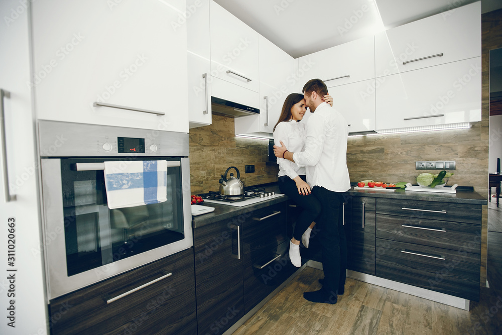 Lovely couple at home in a kithen. Woman and man prepare salad. Woman in a white shirt Lovely couple at home in a kithen. Woman and man prepare salad. Woman in a white shirt