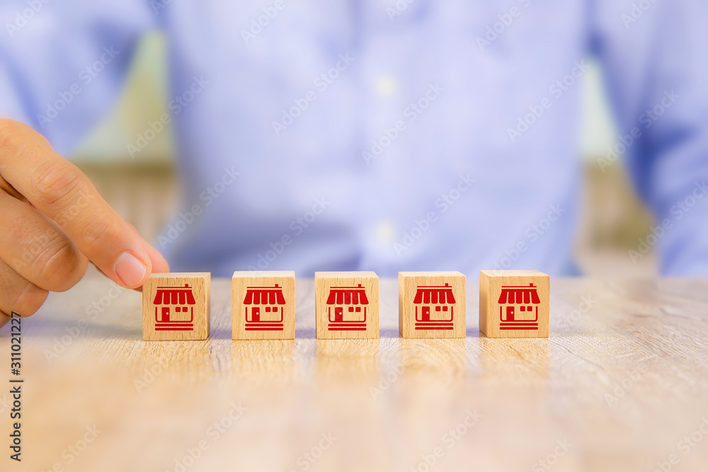 Obraz premium Franchise business,Businessman hand choose wooden blog with franchise marketing icons Store.