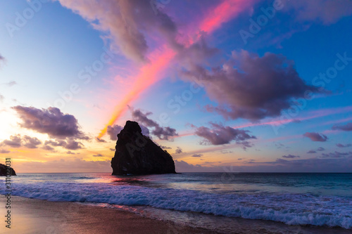 Stunning colorful sunset in Cacimba do Padre beach in Fernando de Noronha, Brazil. Several clouds turned pink forming colorful rays in the sky. photo