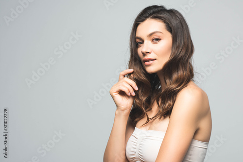 portrait of attractive smiling woman looking at camera, isolated on grey