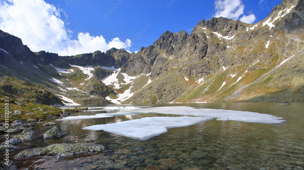 Mountain lake in spring with mighty rocky ridge in the background Mountain lake in spring with mighty rocky ridge in the background
