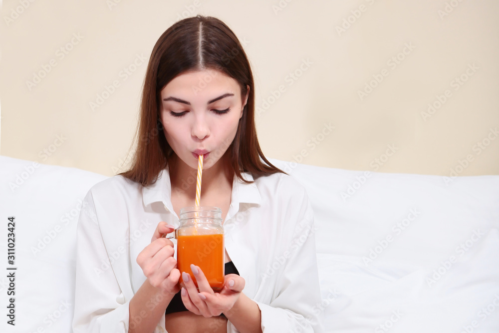 Beautiful girl drinking juice in bed. Breakfast concept at home or in the hotel. Beautiful girl drinking juice in bed. Breakfast concept at home or in the hotel.