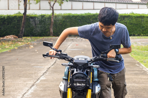 A Biker drives a broken motorcycle along a country road