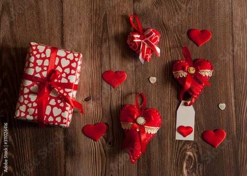 The Concept Of Valentine's Day. Gift boxes and hand sewn textile decorative red hearts with silk ribbons on wooden background.