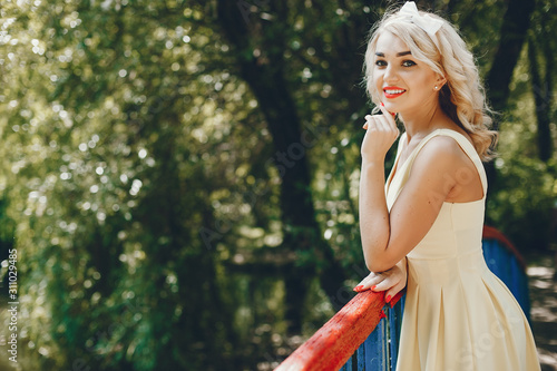 Stylish girl in a retro dress. Vintage lady in a summer park. Pretty woman in a yellow dress