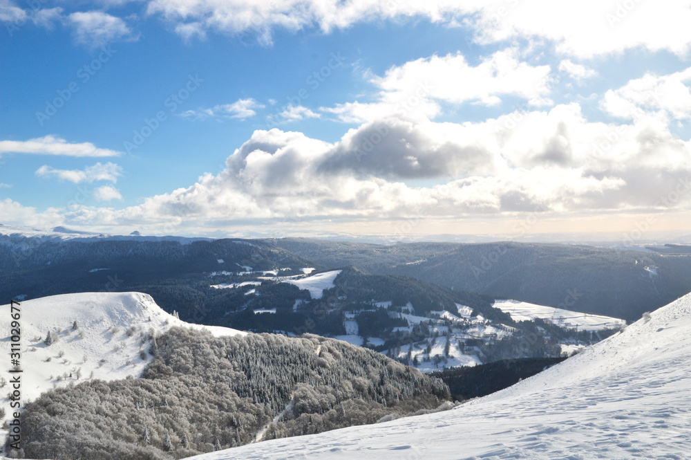 Obraz premium A beautiful viewpoint of the snowy volcanic mountain range during the winter, in Auvergne.