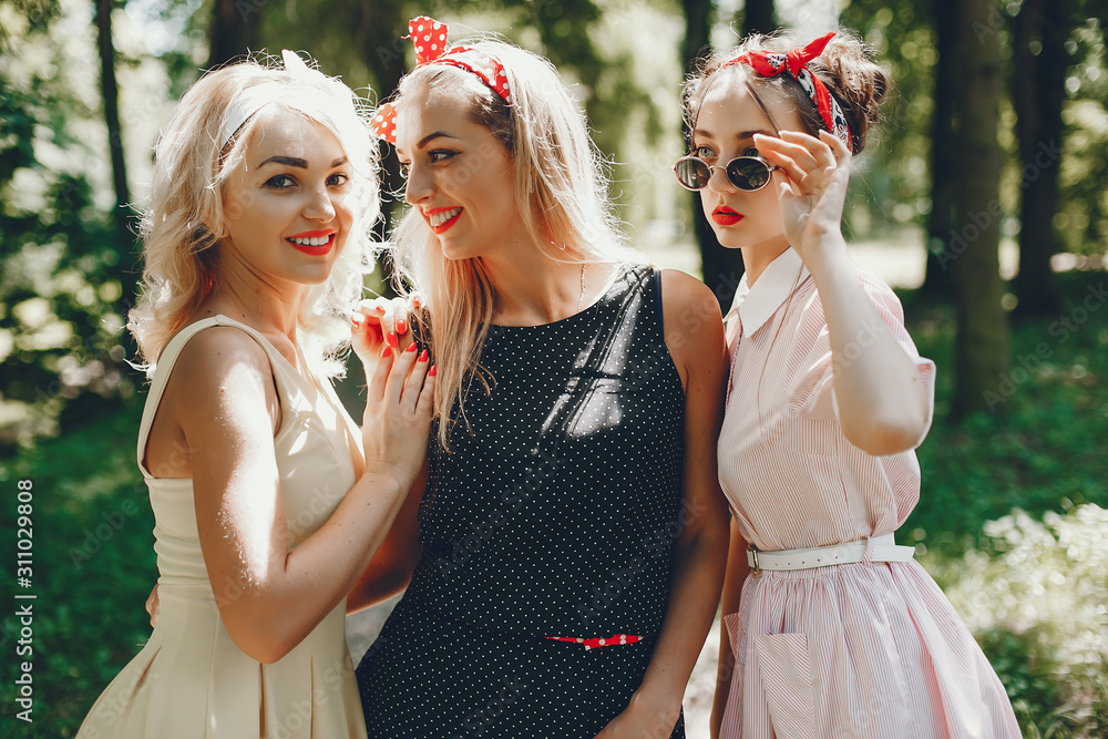Stylish girls in a retro dress. Vintage ladies in a summer park. Three women have fun