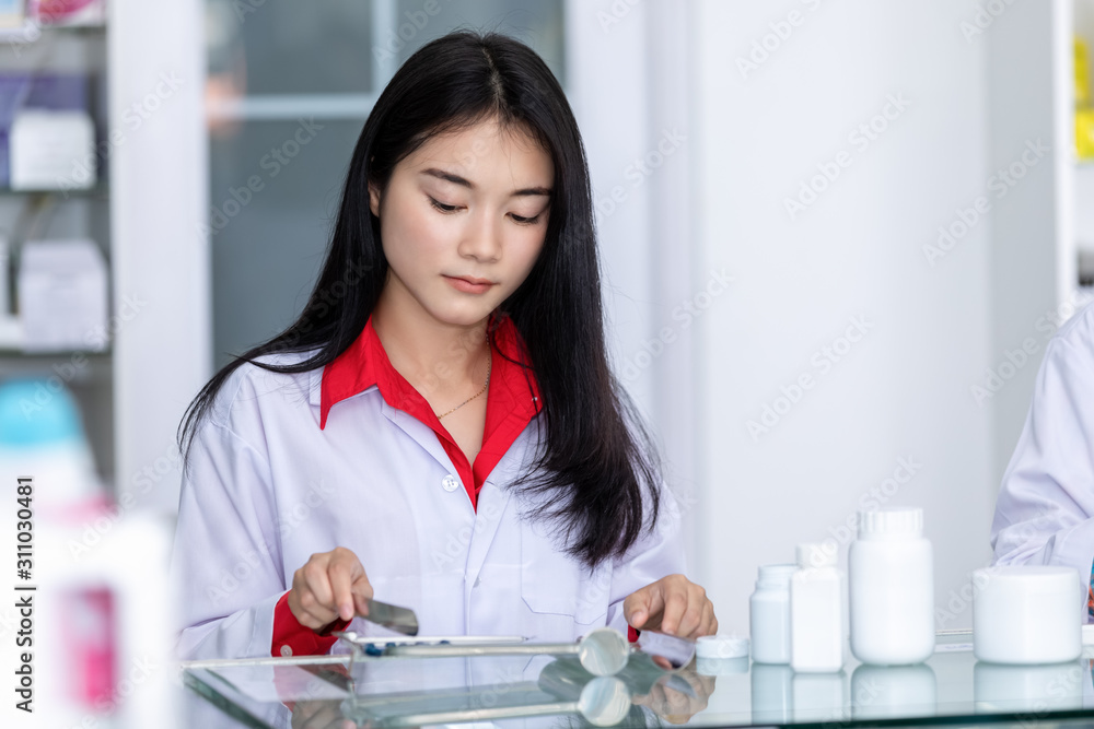 asian pharmacist drug counting on counter in pharmacy