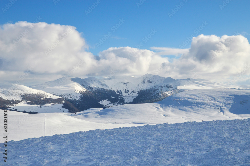 A beautiful viewpoint of the snowy volcanic mountain range during the winter, in Auvergne.