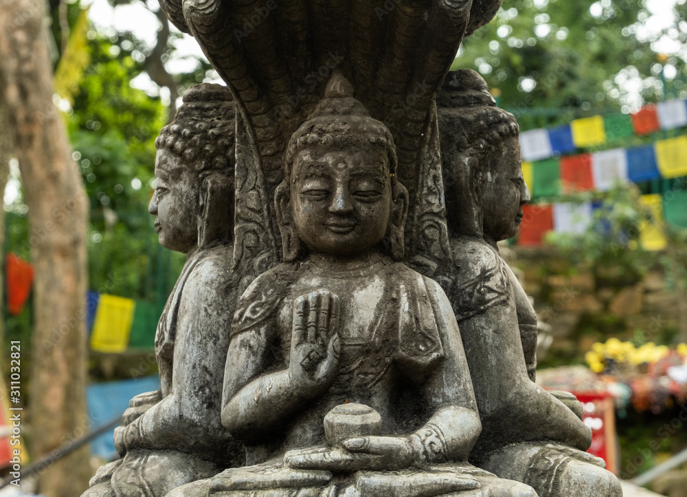 Ancient carved stone pillar with the image of a sitting Buddha and are decorated with traditional Buddhist patterns.