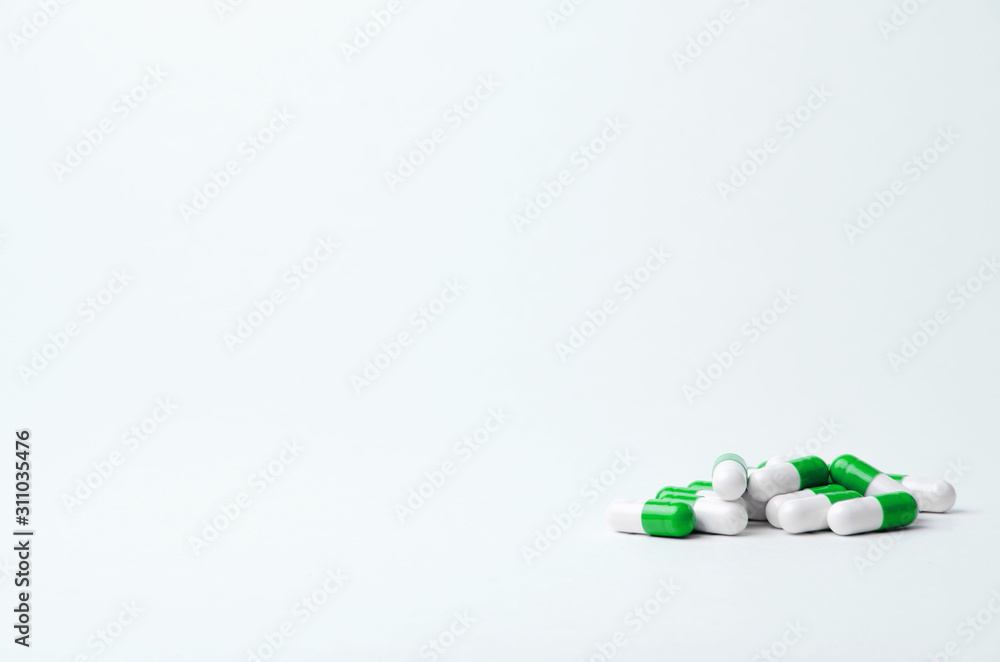 Green and white pills on a light background with place for text. Biological supplements, vitamins, medicines for health. Horizontally.