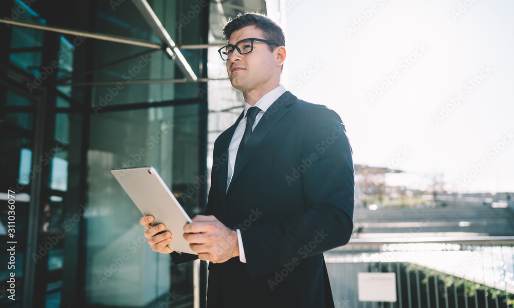 Determined businessman with gadget on street
Handsome young businessman in black suit holding tablet in hands and looking away in sunlight on background of modern city Determined businessman with gadget on street
Handsome young businessman in black suit holding tablet in hands and looking away in sunlight on background of modern city