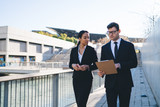 Contemporary business people discussing papers
Modern elegant businesswoman with diverse formal man discussing paper document reading clipboard while walking together on urban background and talking
