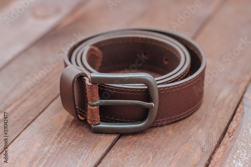 dark brown men's leather belt on a wooden background