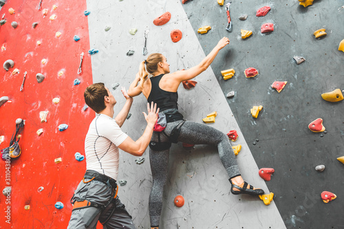 couple of athletes climber moving up on steep rock, climbing on artificial wall indoors. Extreme sports and bouldering concept