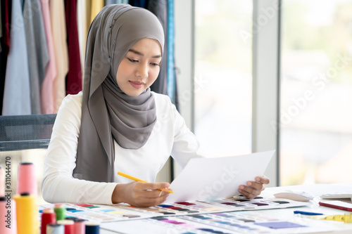 Muslim Creative Fashion Designer is Working owner working in her Tailor Shop.