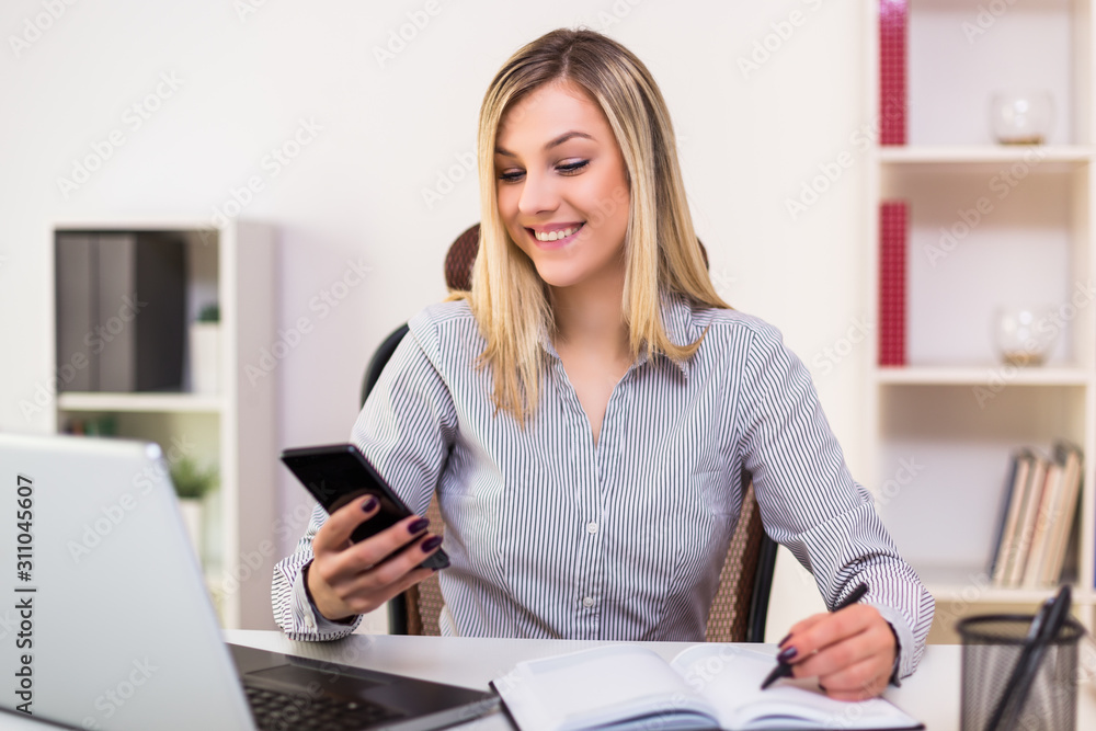 Businesswoman using mobile phone while working in her office. Businesswoman using mobile phone while working in her office.