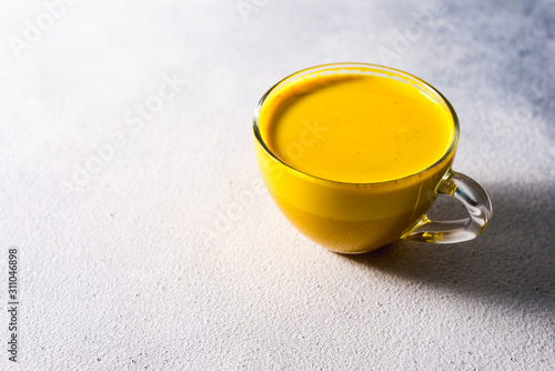 Golden turmeric milk on the white background with spices cinnamon and ingredients