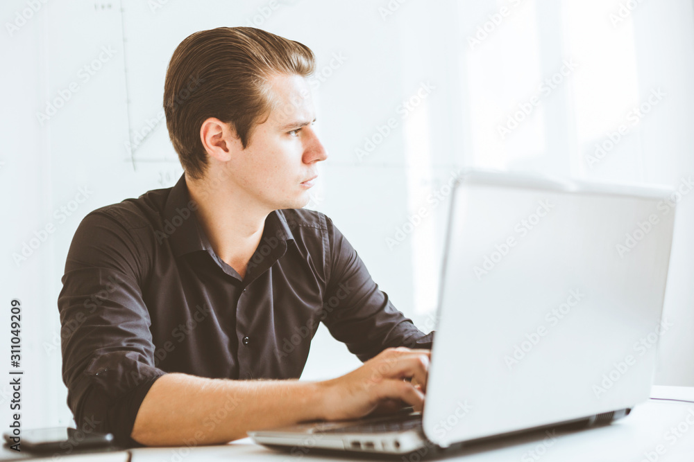 Young businessman working in the office at the laptop Young businessman working in the office at the laptop