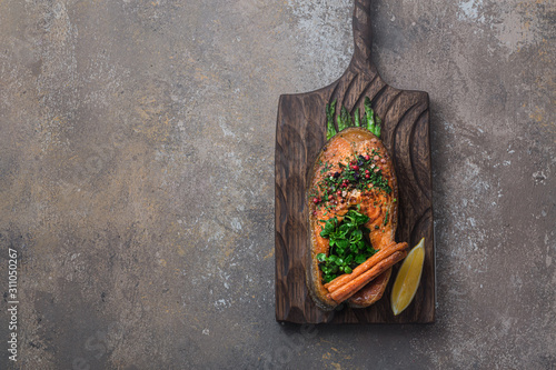 Fried salmon steak with vegetables on wooden board, flat lay copy space