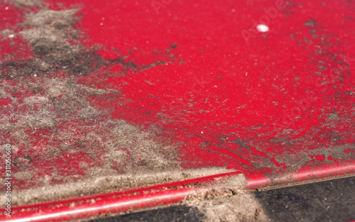 Dirt, mud, and dry pollen on roof of red car not washed for a long time, closeup detail photo
