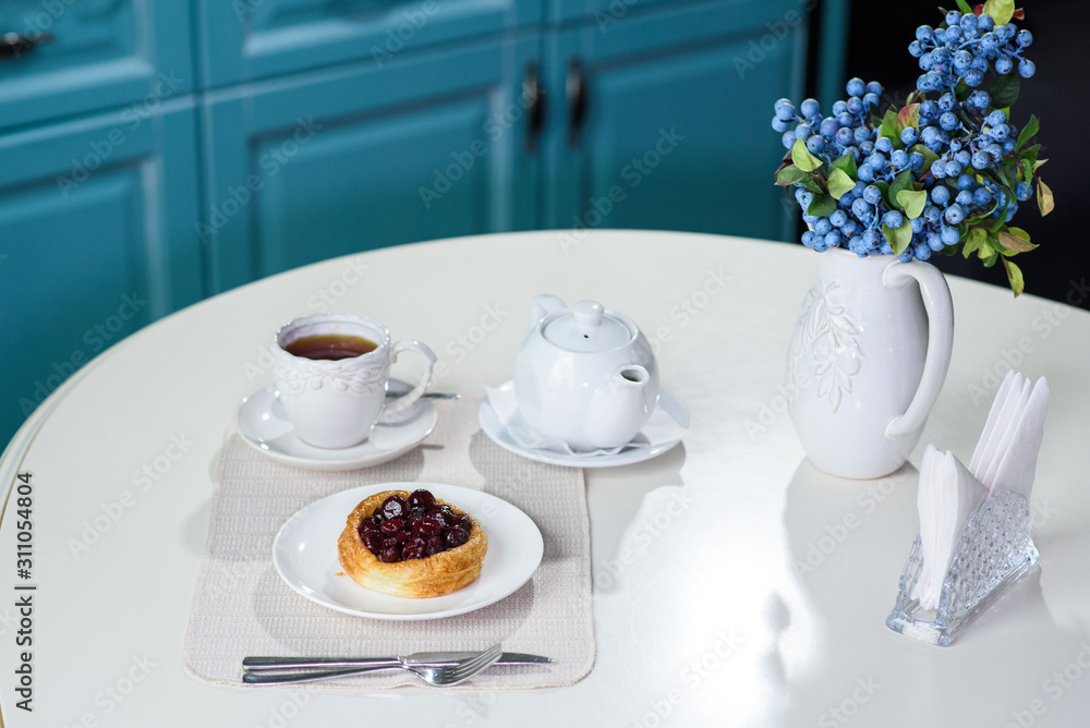 Danish with cherries and black tea on a table in a cozy coffee shop Danish with cherries and black tea on a table in a cozy coffee shop