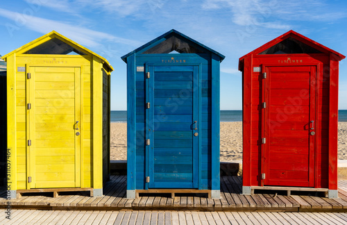 row of beach yellow blue and red huts and cabins with see and beach in background