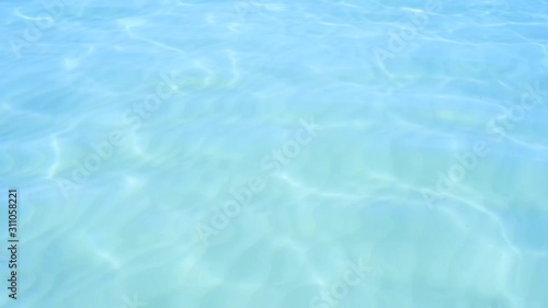 Blue clear ocean water. White sand at the bottom. Solar reflections