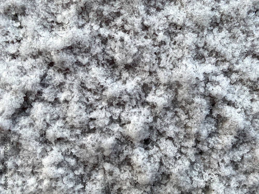 Closed up snowflakes on the ground in winter season. Beautiful contrast between white ice and brown land background.