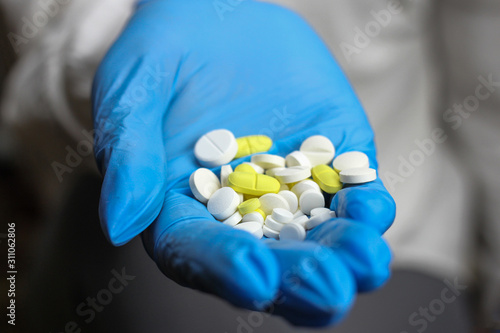 Colorful pills in the hand of a health worker. Blurred background