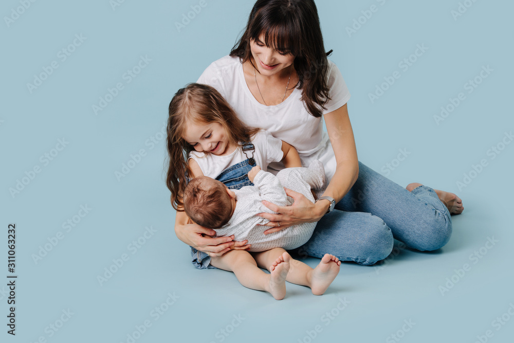 Mom shows her daughter how to hold the baby in her arms