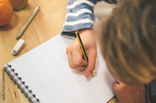 Close up view of student drawing with pencil. Boy doing homework writing on a paper. Kid hold a pencil and draw a manga at home. Teen drawing sitting at the table. Education art talent ability concept