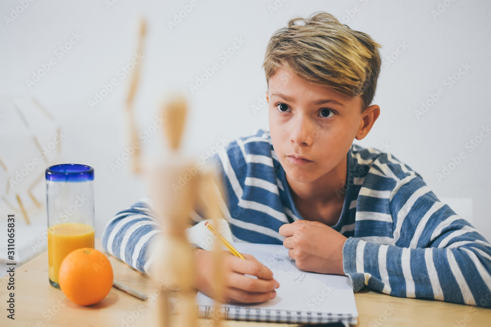 Student drawing with pencil a human figure be inspired by a wooden model. Boy copying a dummy for school art tasks. Kid hold a pencil and draw a manga at home. Education, talent and ability concept. Student drawing with pencil a human figure be inspired by a wooden model. Boy copying a dummy for school art tasks. Kid hold a pencil and draw a manga at home. Education, talent and ability concept.