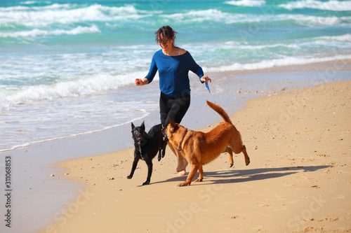 Mature Woman playing with her dogs on the beach.