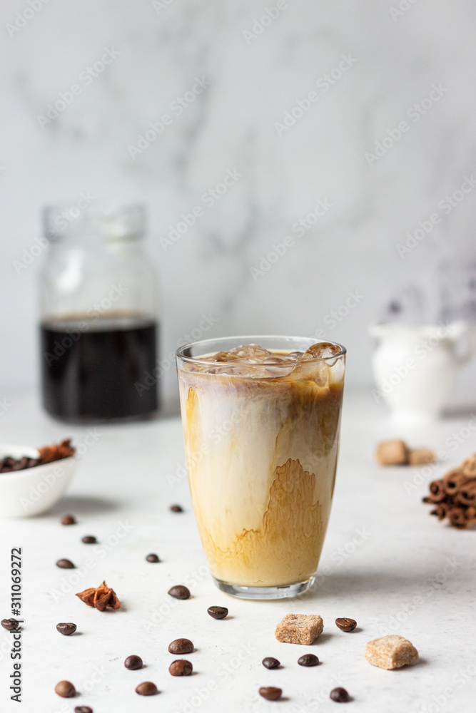 Cold brew coffee with spices and milk on light grey background. Spicy coffee with ice cubes. Cold brew coffee with spices and milk on light grey background. Spicy coffee with ice cubes.