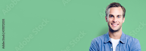 Portrait of happy man, with empty copy space area for slogan, advertising or text message, against green background. Caucasian male model in smart casual clothing, studio picture. Banner composition.