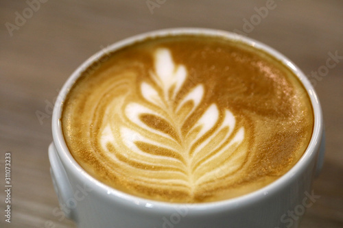 The coffee barista poured milk into the coffee and created a beautiful leaf. © wjarek