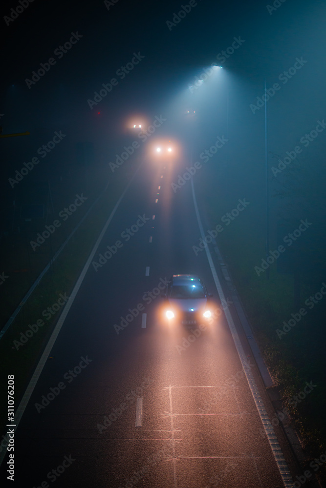 Fogy night on road and lights of cars