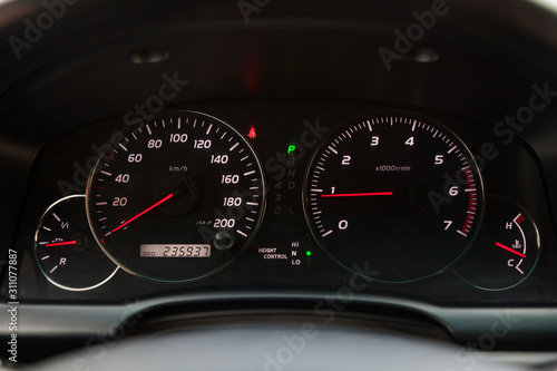 The dashboard of the car is glowing blue with red arrows at night with a speedometer, tachometer and other tools to monitor the condition of the vehicle in modern style on black isolated background