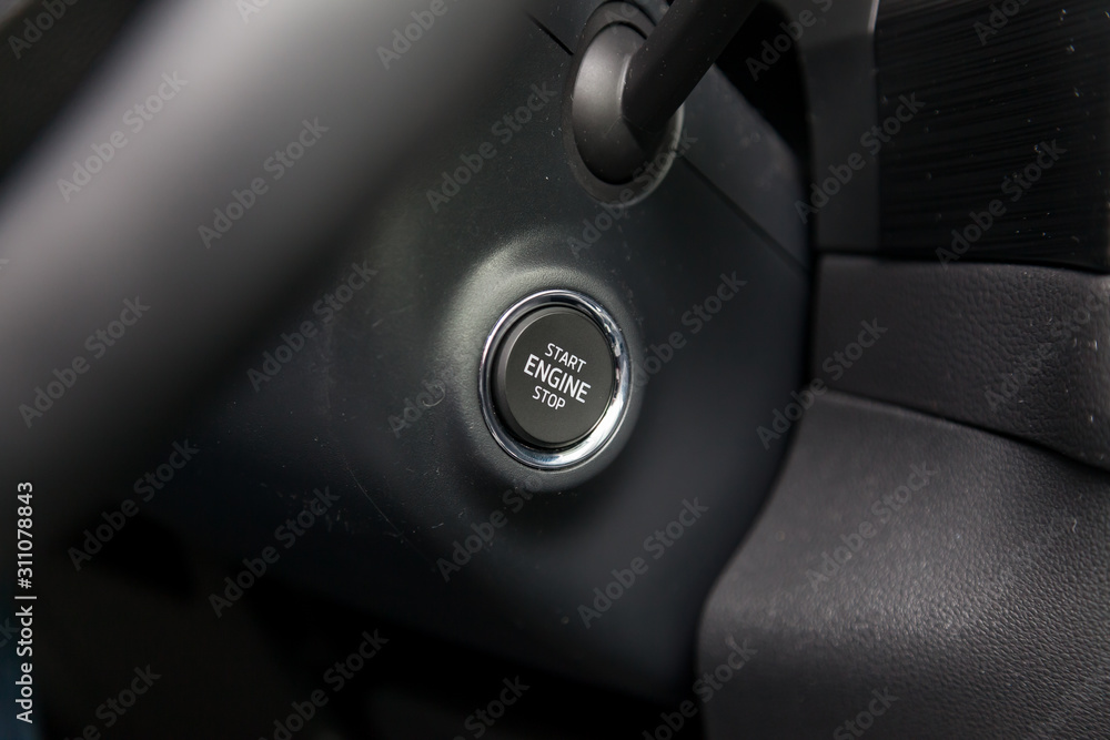 Button start and turn off the ignition of the car engine close-up on the dashboard, electric key, of modern design black and with element chrome on the interior panel