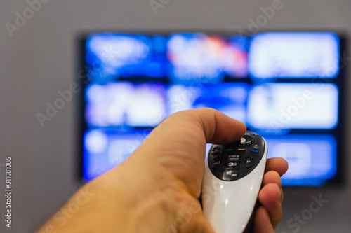 A man holds in his hand TV remote control. The man switches channels, choosing what to watch. Recreation and entertainment concept. Leasure and lifestyle.