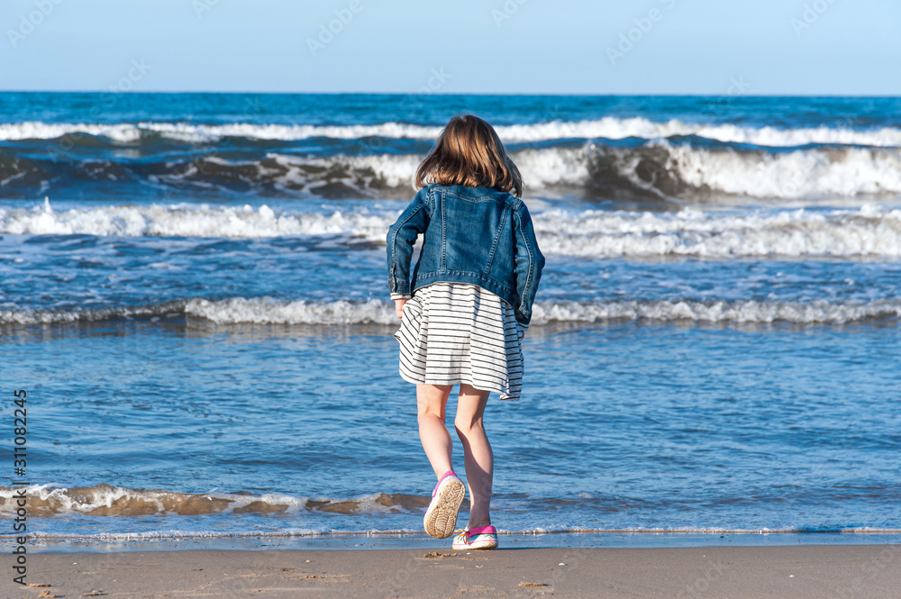 Little girl stepping into sea during her family day out on the beach. Little girl stepping into sea during her family day out on the beach.