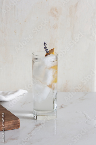Gin Tonic, a cocktail with gin and tonic water, garnished with charred lemon and lavender