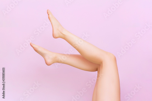 Beautiful long female legs with smooth skin after depilation on a pastel pink background. The concept of clean skin, waxing, shugaring, laser hair removal © Elena
