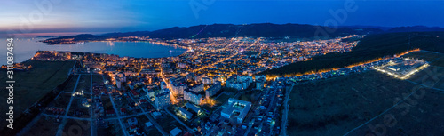 Evening panorama of the seaside resort of Gelendzhik. the sun went down, dark blue sky and sea. Visible Bay, beach and promenade in the lights. The silhouettes of the mountains.
